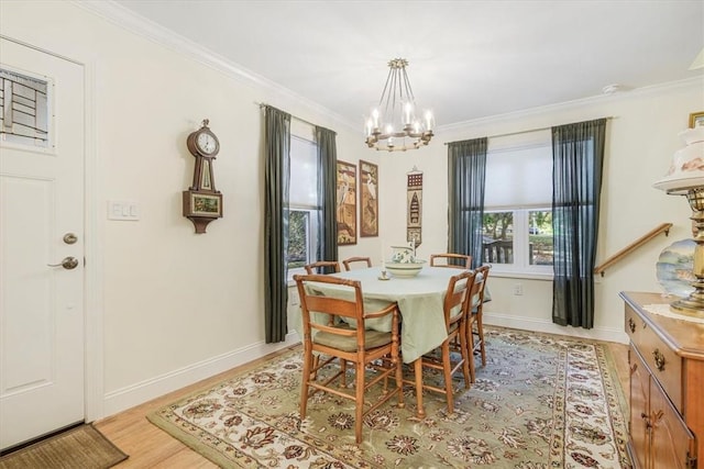 dining room with a chandelier, light wood finished floors, baseboards, and ornamental molding