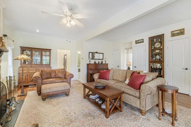 living area with crown molding, ceiling fan, and wood finished floors