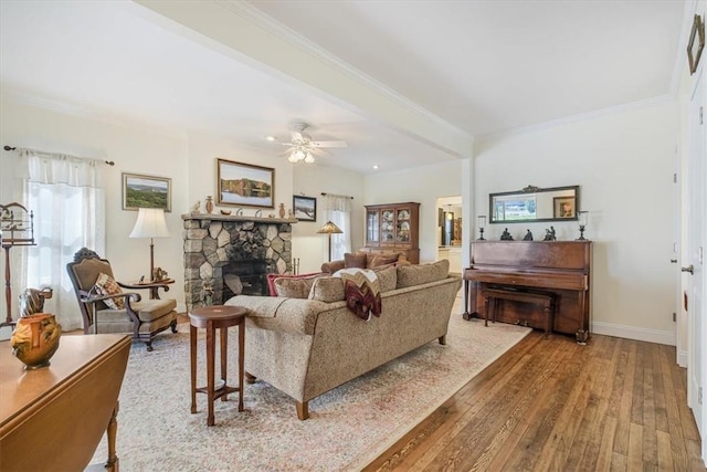 living area with hardwood / wood-style floors, baseboards, a fireplace, ceiling fan, and crown molding