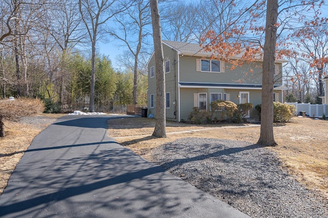 view of side of property with aphalt driveway and fence