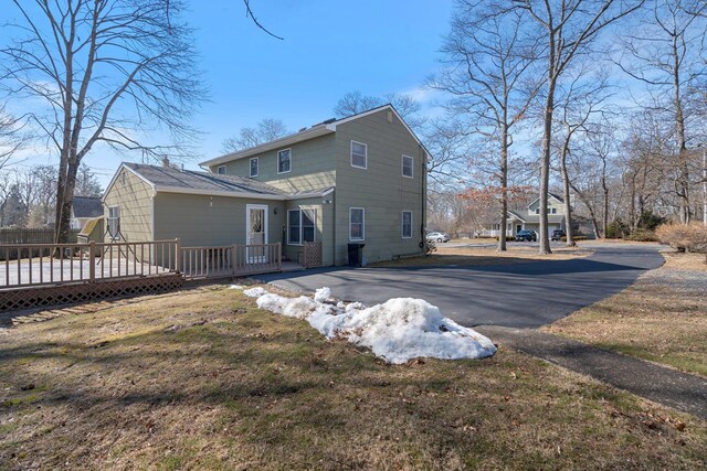 back of house with aphalt driveway and a wooden deck