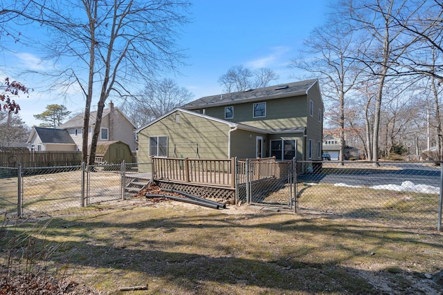 rear view of house featuring a storage shed, a gate, fence private yard, an outdoor structure, and a wooden deck