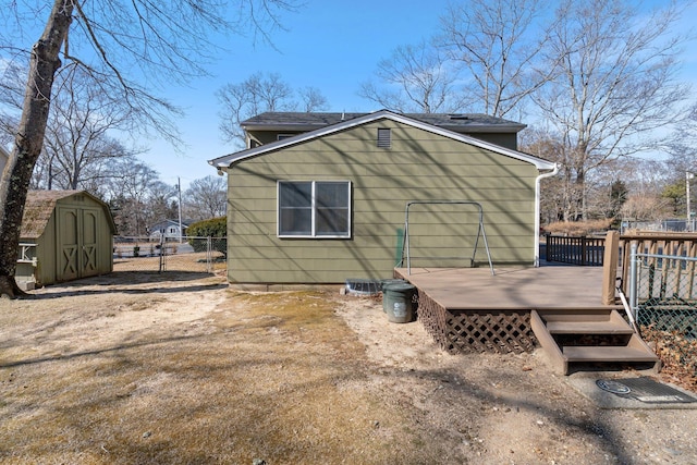 view of property exterior with a wooden deck, fence, a storage unit, and an outbuilding