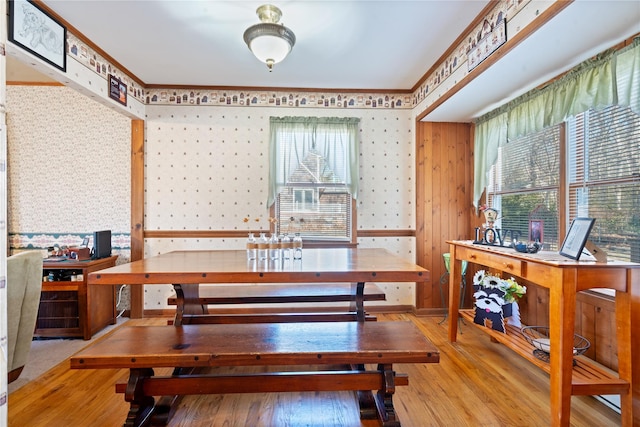 dining space with wallpapered walls, wood-type flooring, and crown molding