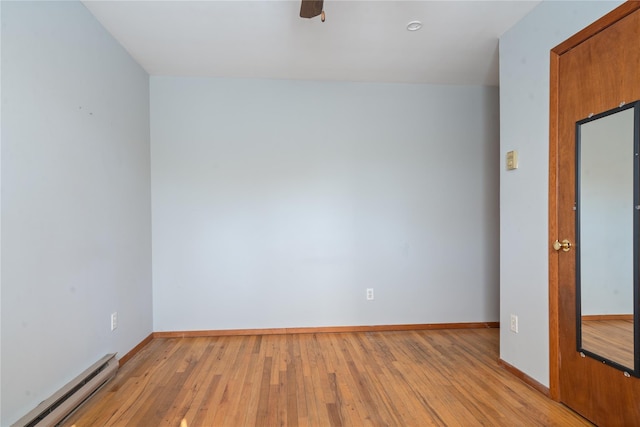 empty room with light wood-style floors, baseboards, and a baseboard heating unit