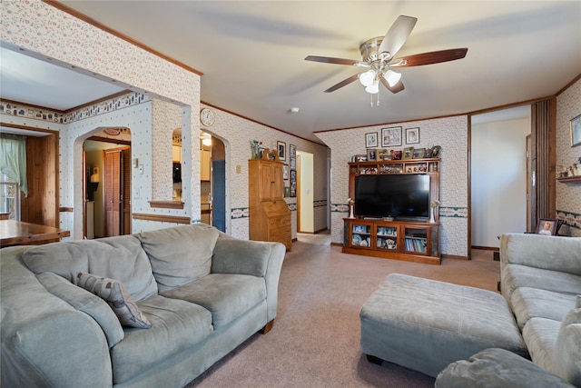 living area featuring wallpapered walls, arched walkways, crown molding, and light colored carpet