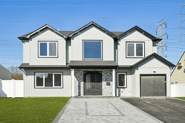 modern farmhouse style home with aphalt driveway, an attached garage, fence, roof with shingles, and a front lawn