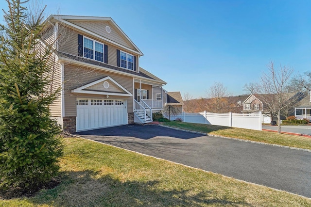 view of front of property featuring an attached garage, fence, stone siding, and driveway