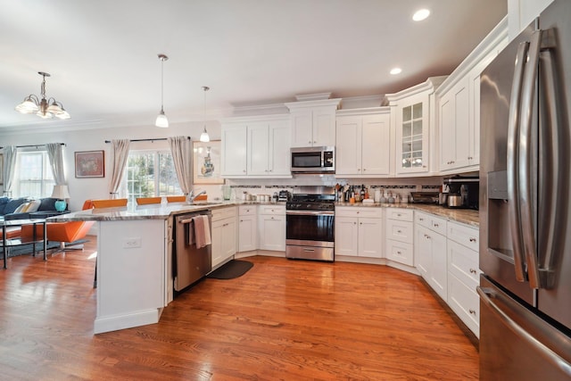 kitchen with tasteful backsplash, open floor plan, a peninsula, stainless steel appliances, and a sink