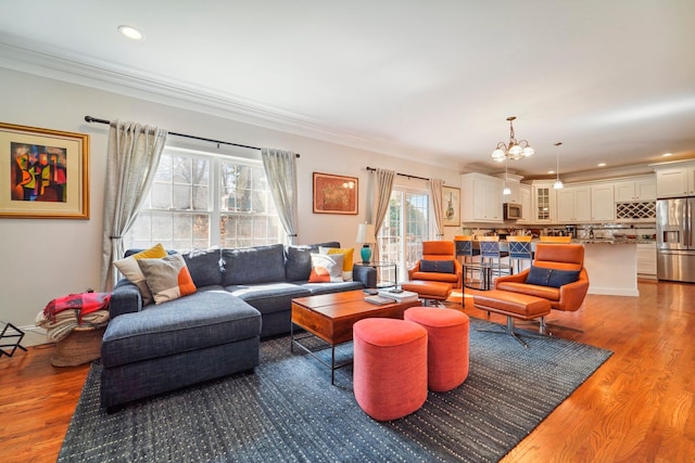 living area with crown molding, a notable chandelier, wood finished floors, and recessed lighting