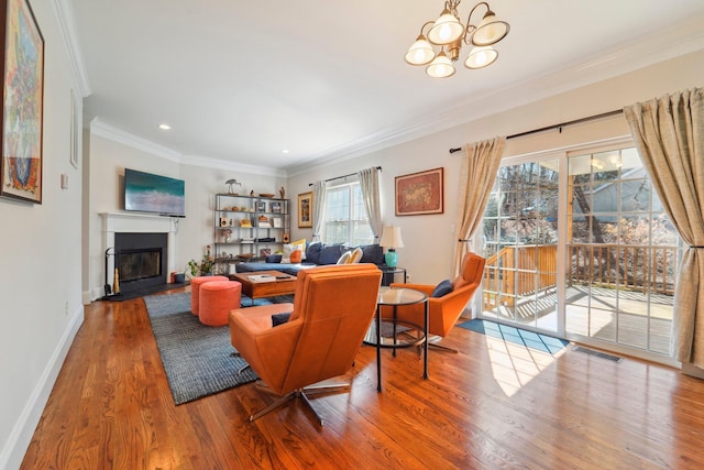 living area featuring visible vents, crown molding, baseboards, wood finished floors, and a glass covered fireplace