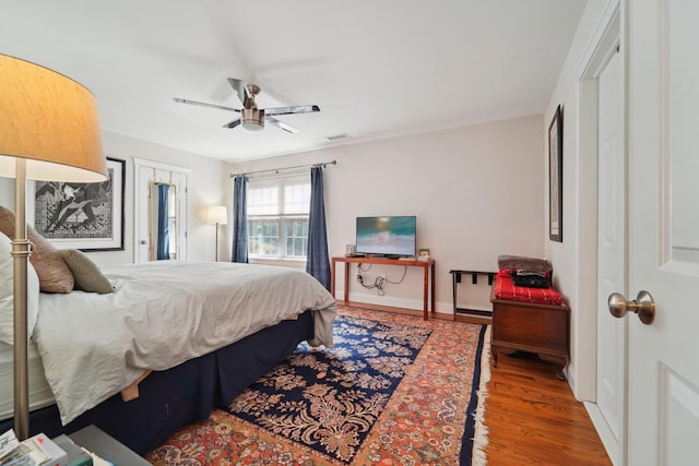 bedroom featuring baseboards, wood finished floors, visible vents, and ceiling fan