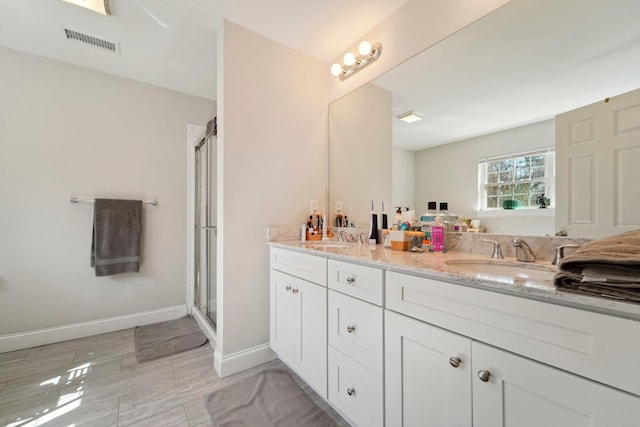 full bath featuring double vanity, visible vents, a shower stall, and a sink