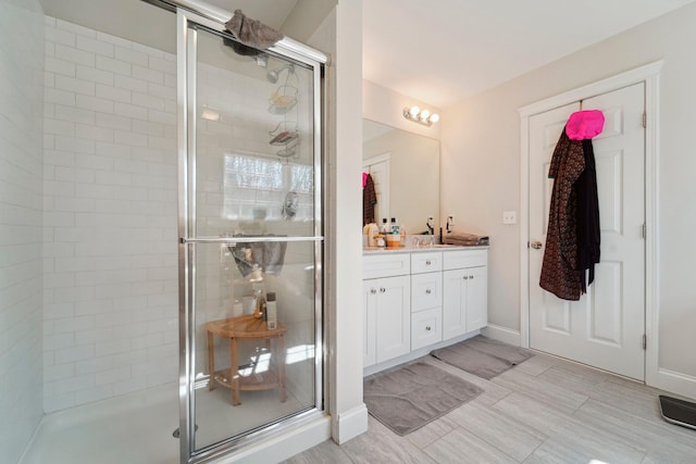 full bath with vanity, a shower stall, and baseboards