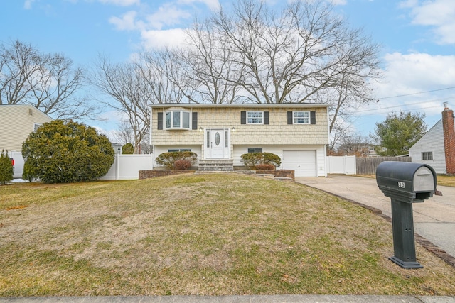 split foyer home featuring entry steps, concrete driveway, an attached garage, fence, and a front yard