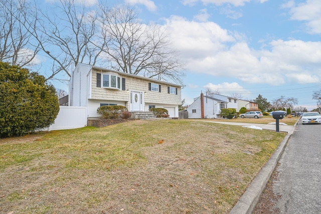 bi-level home with a garage, fence, and a front lawn