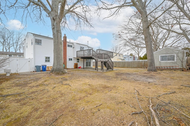 view of yard with stairs, a deck, a fenced backyard, and a gate