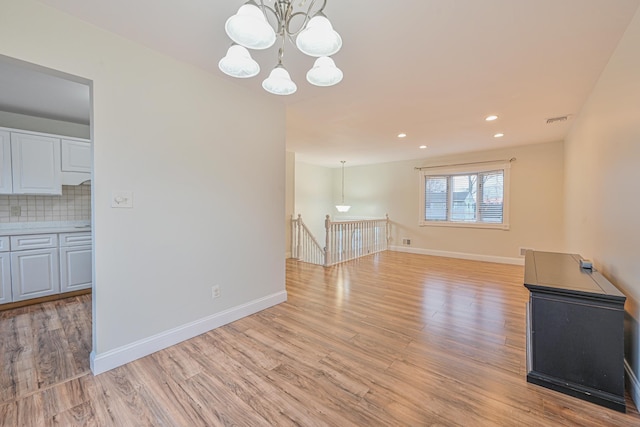 unfurnished living room with visible vents, baseboards, light wood-style flooring, a chandelier, and recessed lighting