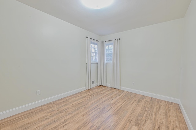 spare room featuring light wood finished floors and baseboards