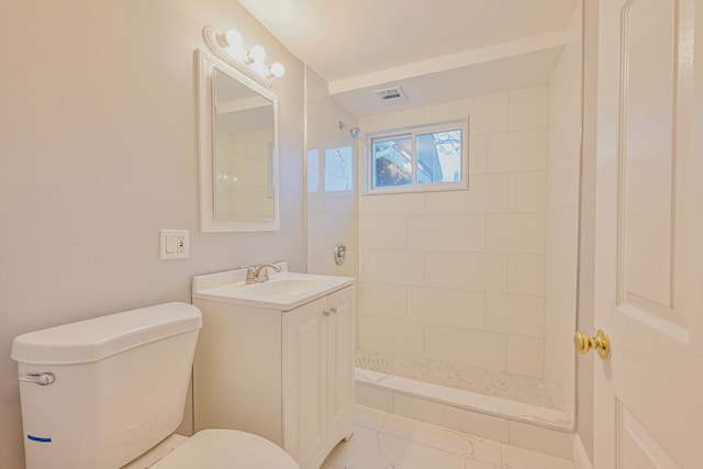 bathroom featuring toilet, visible vents, tiled shower, and vanity