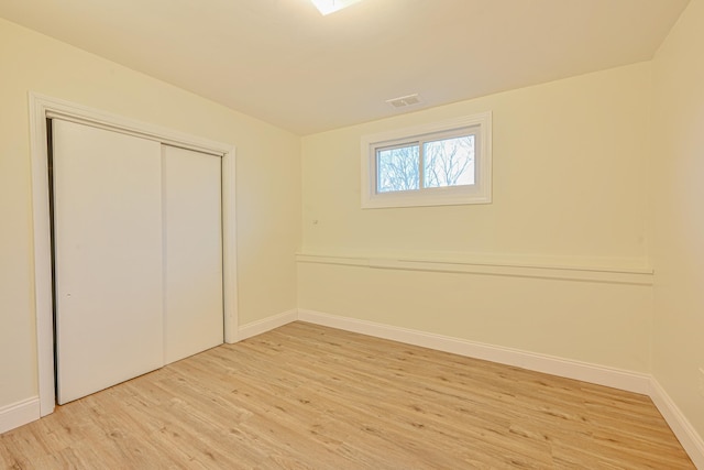 unfurnished bedroom with light wood-type flooring, baseboards, visible vents, and a closet