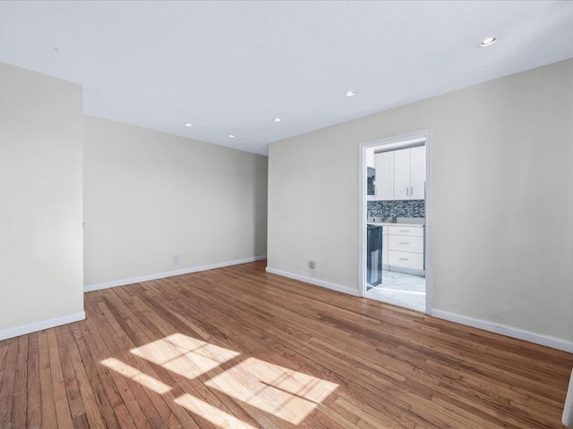 empty room featuring recessed lighting, baseboards, and light wood finished floors