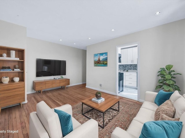 living area featuring baseboards, wood finished floors, and recessed lighting