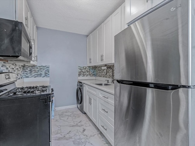 kitchen featuring white cabinetry, appliances with stainless steel finishes, and washer / clothes dryer