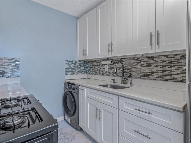 kitchen with marble finish floor, light countertops, white cabinets, a sink, and washer / dryer