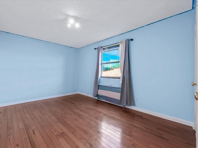 unfurnished room featuring hardwood / wood-style flooring, baseboards, and a textured ceiling