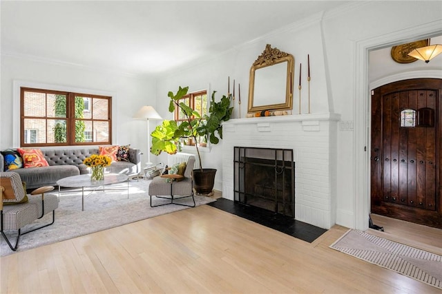 living area with a fireplace, arched walkways, wood finished floors, and ornamental molding