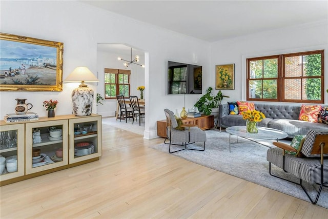 living area with ornamental molding, a notable chandelier, and wood finished floors