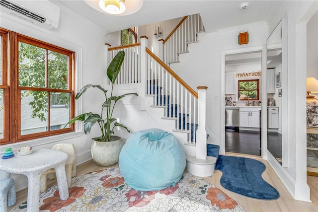 entryway with ornamental molding, a wall mounted air conditioner, wood finished floors, and a wealth of natural light