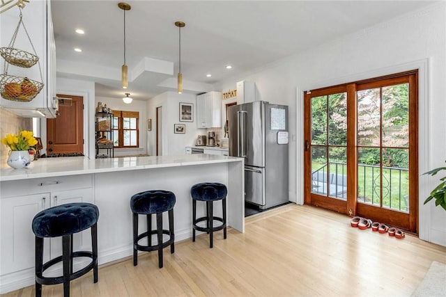 kitchen with a peninsula, light wood-type flooring, light countertops, and freestanding refrigerator