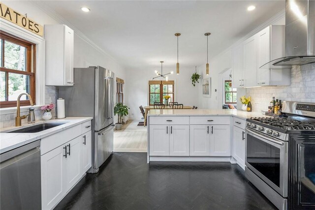 kitchen with stainless steel appliances, white cabinetry, a sink, wall chimney range hood, and a peninsula