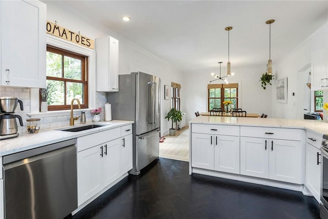 kitchen featuring a peninsula, a sink, white cabinetry, appliances with stainless steel finishes, and backsplash