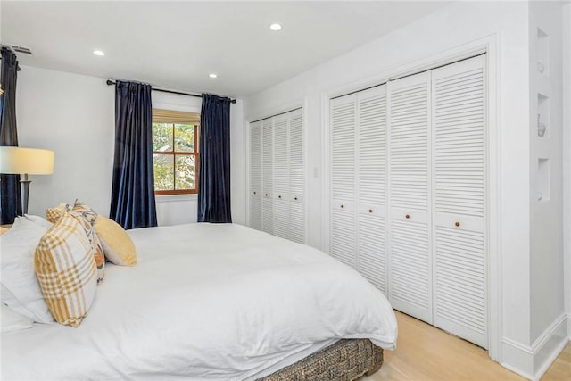 bedroom featuring light wood-style floors, baseboards, two closets, and recessed lighting