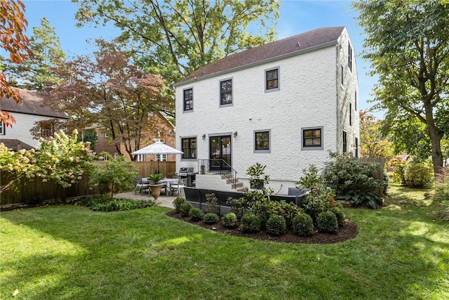 back of house featuring a yard, a patio area, fence, and stucco siding