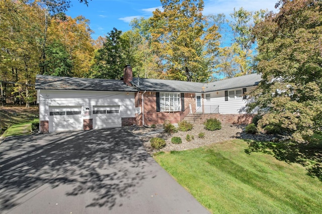 ranch-style home featuring driveway, a front yard, an attached garage, brick siding, and a chimney