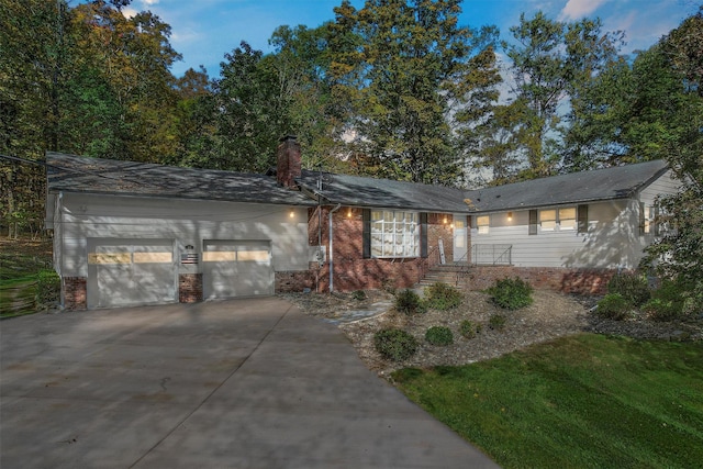 single story home with a chimney, concrete driveway, a garage, and brick siding