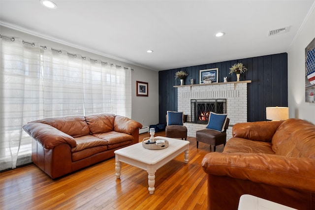 living area featuring visible vents, a brick fireplace, crown molding, recessed lighting, and light wood-style floors