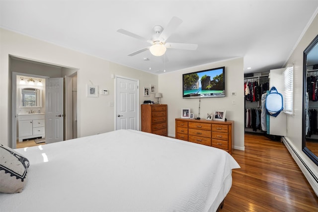 bedroom featuring ceiling fan, baseboard heating, wood finished floors, a closet, and ensuite bath