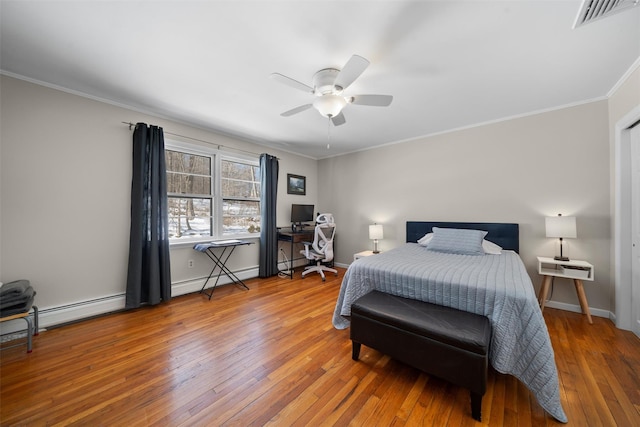 bedroom featuring visible vents, baseboards, ornamental molding, hardwood / wood-style floors, and a baseboard radiator