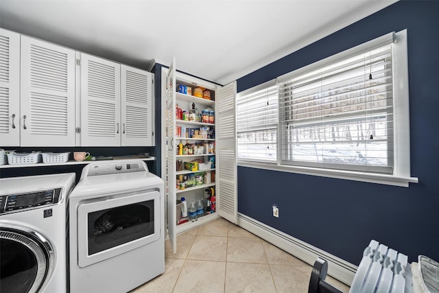 clothes washing area featuring washer and clothes dryer, light tile patterned floors, cabinet space, and baseboards