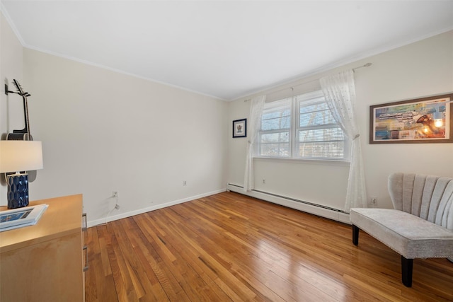 sitting room featuring baseboard heating, ornamental molding, baseboards, and hardwood / wood-style floors