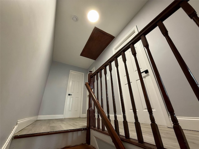 staircase featuring baseboards and wood finished floors