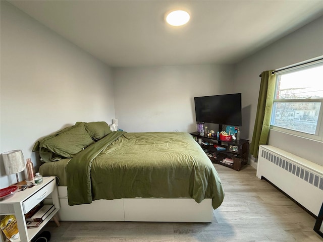 bedroom with light wood-style floors and radiator heating unit