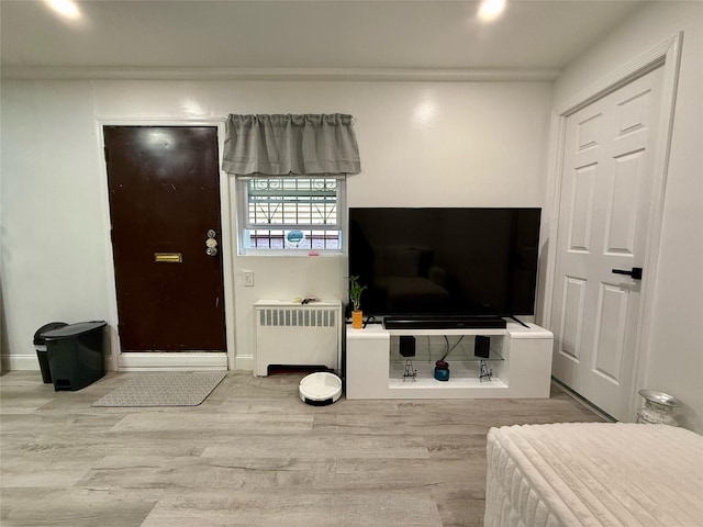 living area with radiator, baseboards, and wood finished floors