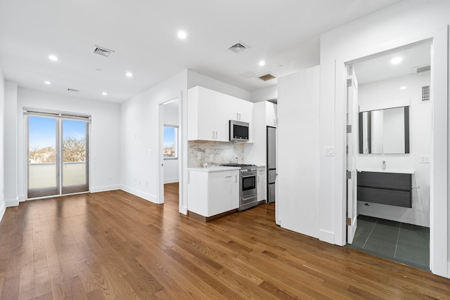 kitchen with stainless steel appliances, dark wood-type flooring, visible vents, white cabinets, and light countertops