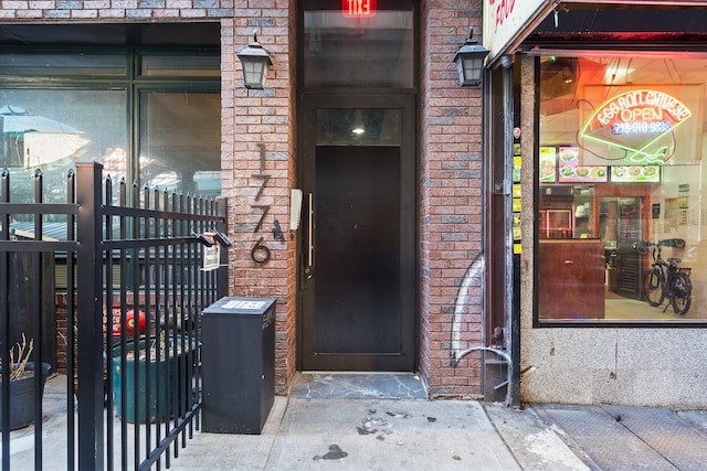 doorway to property with brick siding and fence